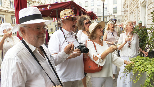Eine Gruppe von weiß gekleideten älteren Menschen feiert in Wien den elfjährigen Prinz George.