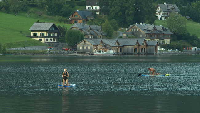Auf einem See im Salzkammergut sind einige Wassersportler zu sehen.