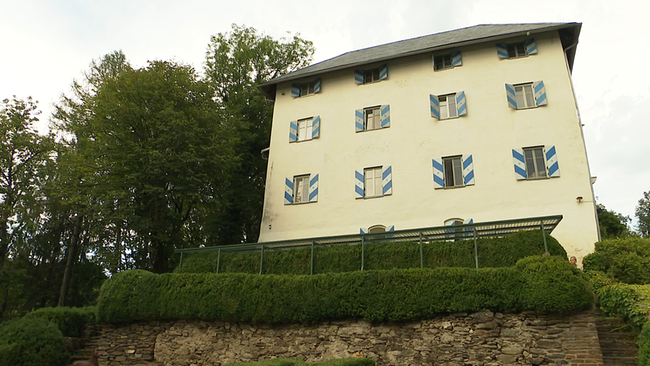 Ein renoviertes kleines Schloss steht auf einem kleinen Kärntner Hügel.