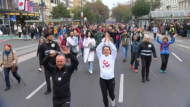 Auf der Wiener Ringstrasse sind tausende Menschen zu Fuß unterwegs. 