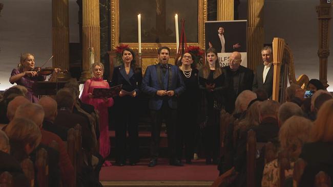 Eine Gruppe Menschen steht vor dem Altar einer Kirchen und singt...