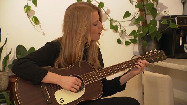 Verena Koppendorfer sitzt mit Gitarre auf einem Hocker