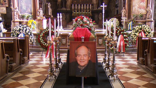 In einer Kirche ist ein Sarg mit einem Foto davor zu sehen. 