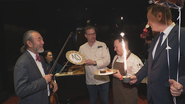 Ein älterer Mann bekommt eine Torte überreicht. 