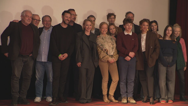 Eine Gruppe von Schauspieler posiert auf einer Bühne für Fotografen