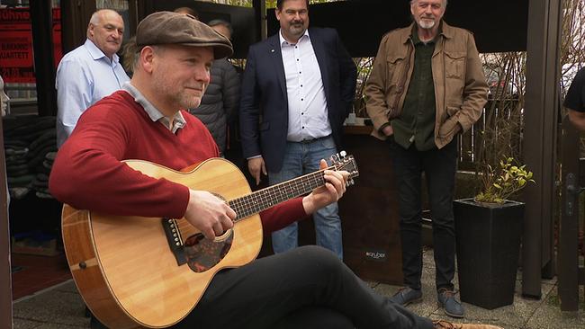 Ein Mann mit Schirmmütze spielt auf einer Gitarre.