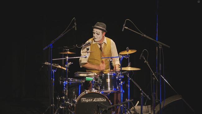 Budi Butenop sitzt mit einer geschminkten Clownmaske am Schlagzeug auf der Bühne 