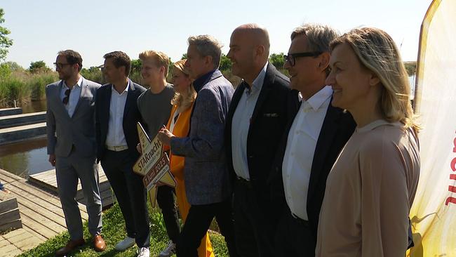 © ORF / Seitenblicke Eine Gruppe Menschen posiert mit einem Schild auf dem "Starnach am Neusiedler See" steht für die Kameras.