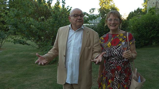 Ein Mann und eine Frau schauen in einem Park in die Kamera.