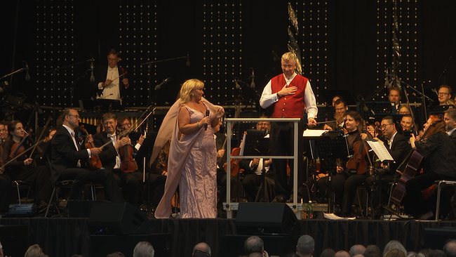 © ORF / Seitenblicke Eine Sängerin, ein Dirigent und ein Orchester sind zu sehen.