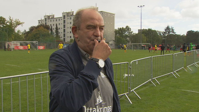 Fußballlegende Herbert Prohaska steht mit Pfeife im Mund am Fußballplatz 