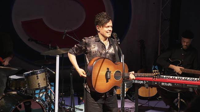 Ein Musiker steht lächeld auf einer Bühne...