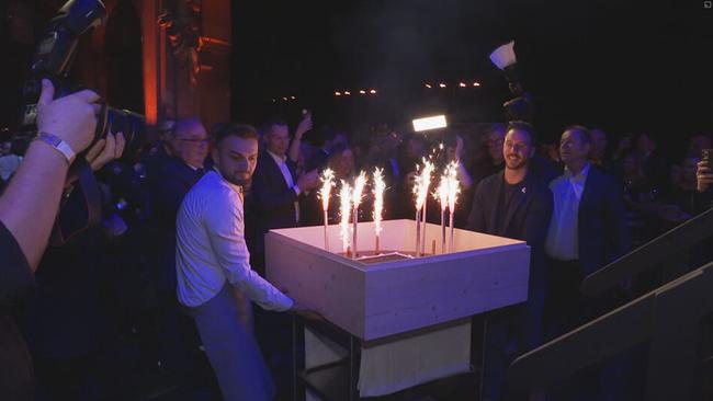 © ORF / Seitenblicke zwei Männer schieben eine Torte mit Sprühkerzen durch die Menge