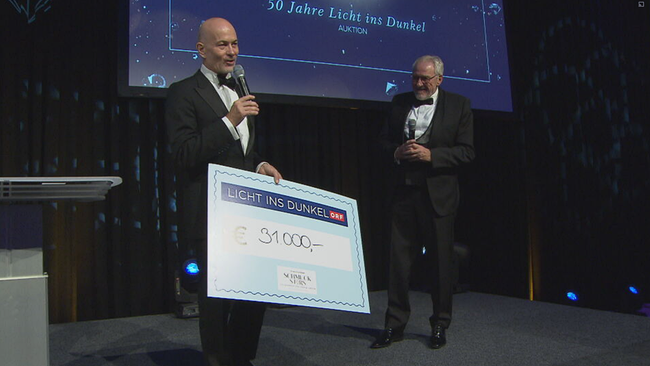 Christian Lerner und Pius Strobl präsentieren den 31.000€ Scheck zugunsten von Licht ins Dunkel auf der Bühne 