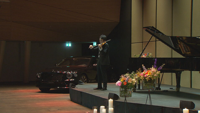 Violinist Ziyu He steht in schwarzem Anzug und seiner Geige auf der Bühne und spielt. 