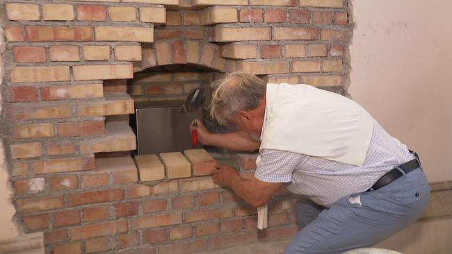 Hans Peter Haselsteiner klopft einen Ziegelstein in die Wand