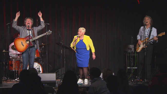 Sängerin Jazz Gitti steht mit ihrer Band auf der Bühne der Wiener Casanova Bar und singt. Ihre Kleidung hat sie farblich an die ukrainischen Nationalfraben angepasst: Gelbe Jacke, blaues Kleid