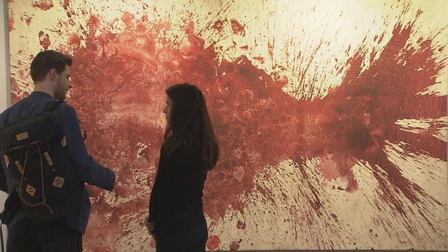 Zwei BesucherInnen stehen vor einem Schüttbild von Hermann Nitsch 