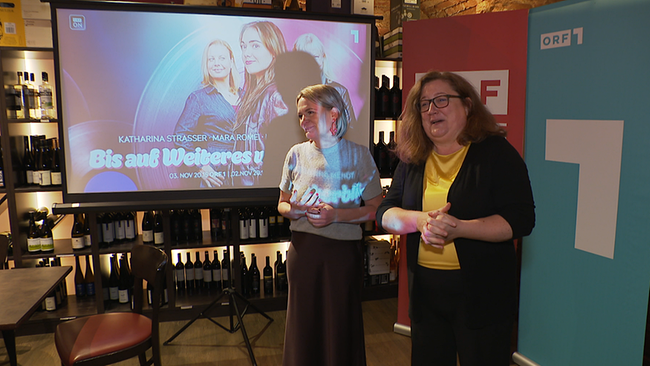 2 Frauen stehen vor einem Bildschirm 