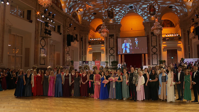 © ORF / Seitenblicke Die Wiener Hofburg von innen mit einer großen Menge an Menschen auf dem Tanzparkett, beim Posieren für ein Gruppenfoto.