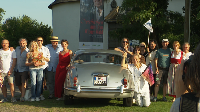 Eine Gruppe von Menschen posieren für ein Foto mit einem Oldtimer in der Mitte