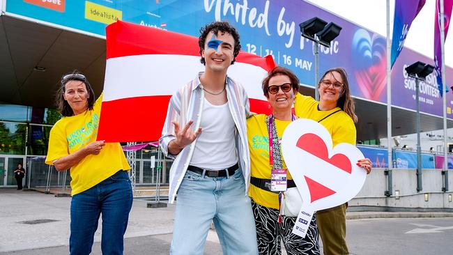 © ORF/Roman Zach-Kiesling COSMÓ und drei Volunteers posieren vor der Wiener Stadthalle mit österreichischer Flagge und Herzsymbolen in Fan‑Outfits.