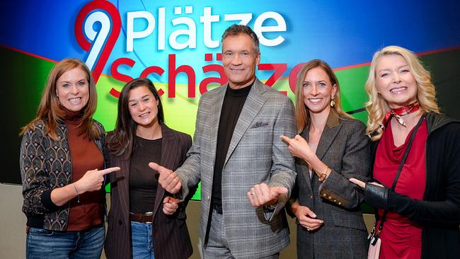 © ORF/Roman Zach-Kiesling Maria Theiner, Daniela Schmiderer, Armin Assinger, Veronika Kaizar und Elisabeth Vogel posieren lächelnd vor dem Logo der ORF-Sendung „9 Plätze – 9 Schätze“.
