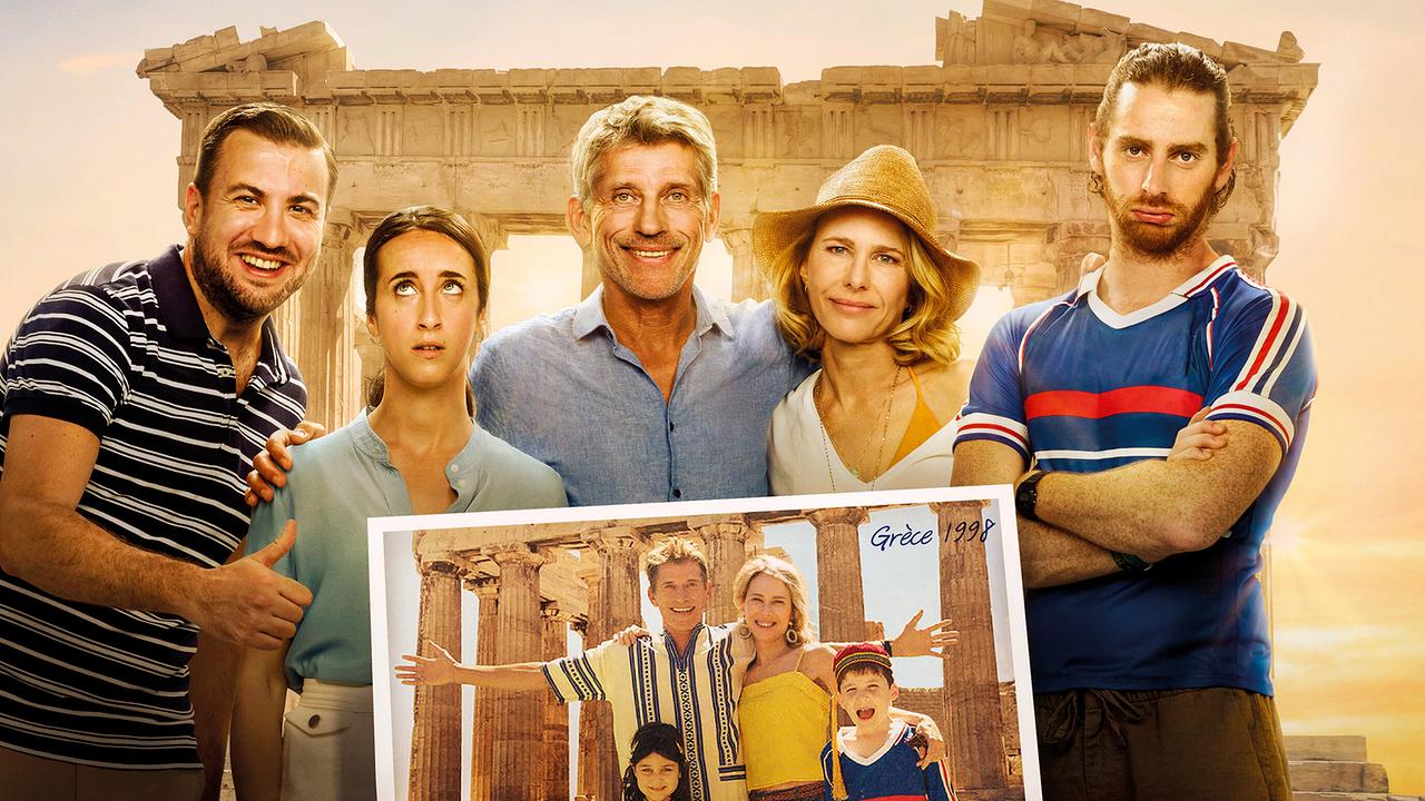 © ORF/Happy Entertainment/Céline Nieszawer Christophe, Karine Hamelin, Thierry Hamelin, Claire Hamelin und Antoine Hamelin stehen vor der Akropolis, während im Vordergrund ein altes Urlaubsfoto derselben Gruppe an diesem Ort in die Kamera gehalten wird.
