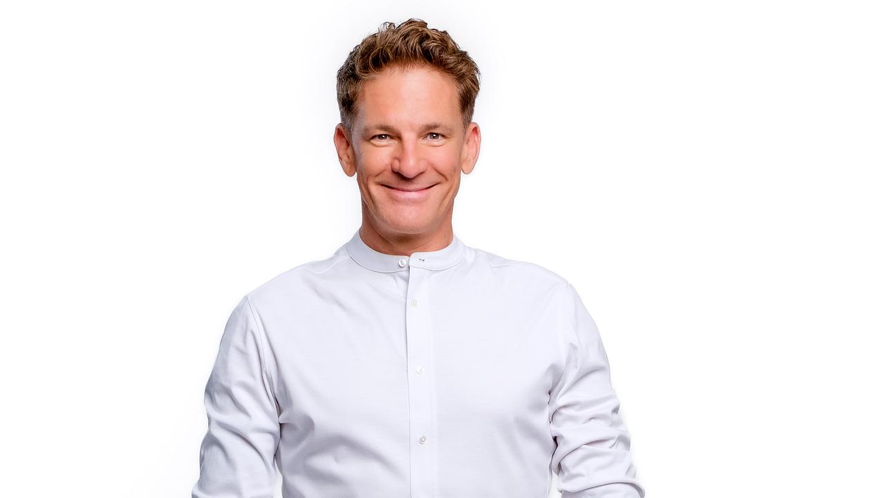 Andi Knoll steht vor weißem Hintergrund und trägt ein schlichtes, helles Hemd mit dunkler Hose in einer neutralen Studioaufnahme.
