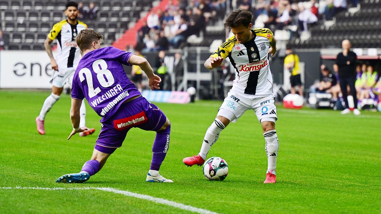  Philipp Wiesinger (FK Austria Wien) und Sascha Horvath (LASK Linz) im Zweikampf um den Ball während eines Spiels im Stadion mit Zuschauern im Hintergrund in Linz.