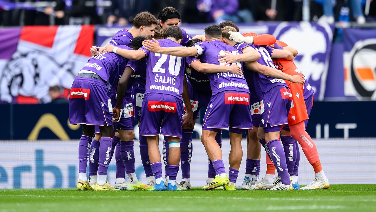 © APA/MAX SLOVENCIK Das Team von FK Austria Wien in violetten Trikots steht im Kreis vor einer dicht gefüllten Fankurve im Rahmen der Admiral Bundesliga-Begegnung zwischen FK Austria Wien und LASK in Wien.