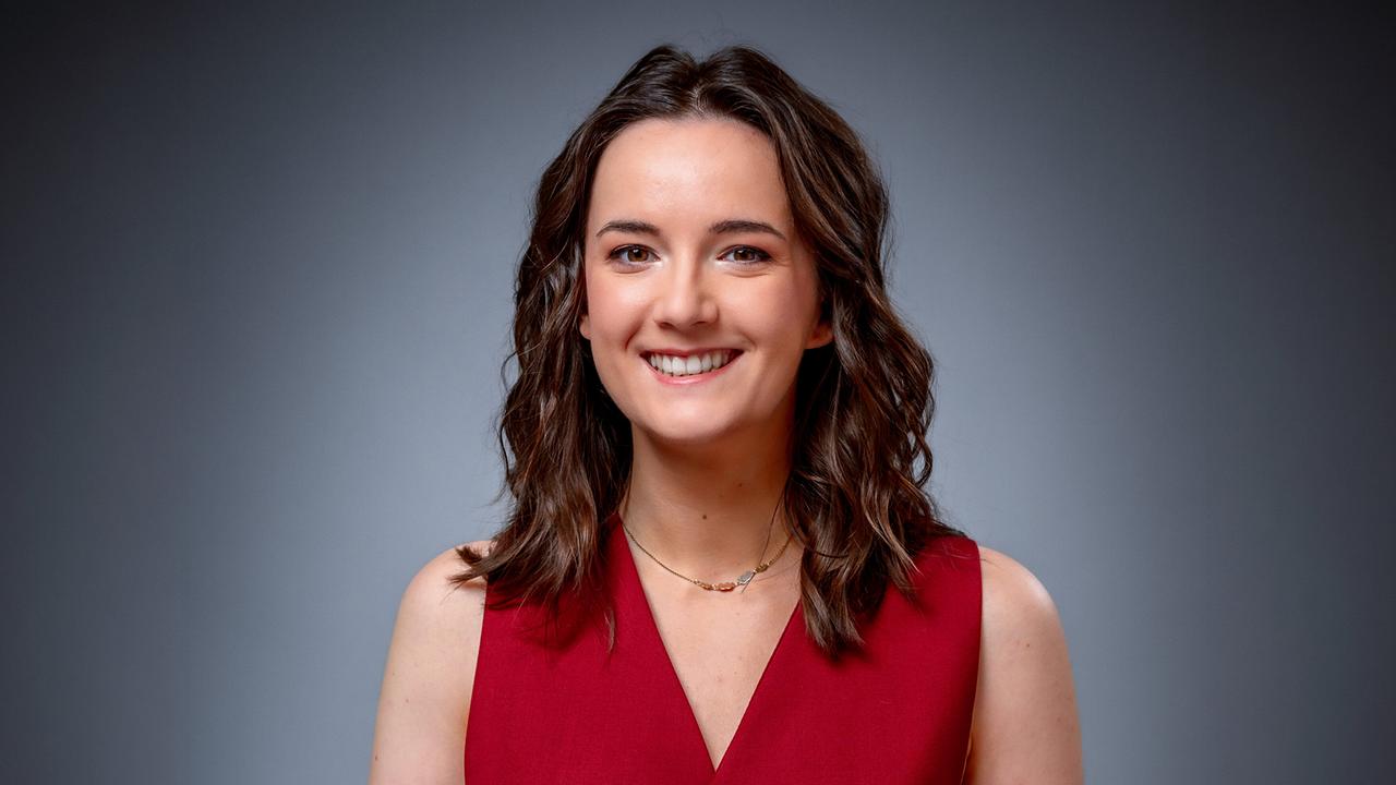 Portrait of Emily Busvine in a red top against a gray background