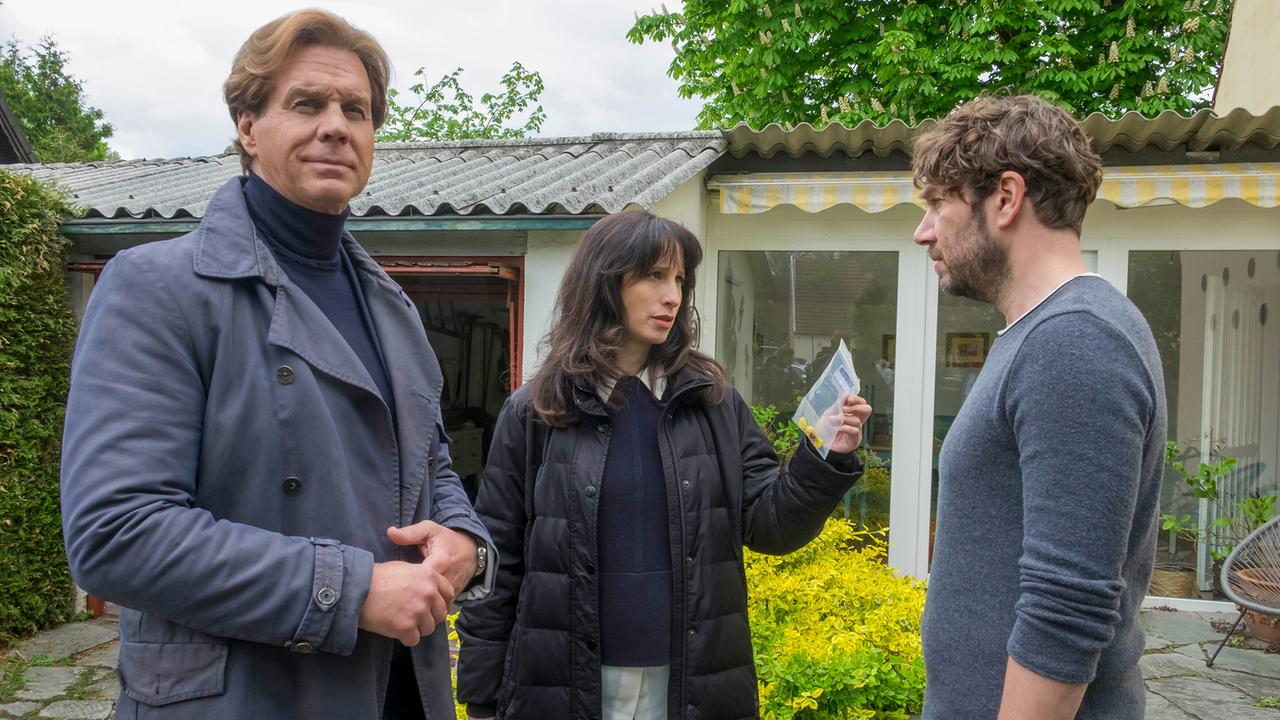 Caspar Bergmann und Annabell Lorenz stehen mit Martin Kessler im Garten eines Hauses und konfrontieren ihn mit einem Beweisstück.