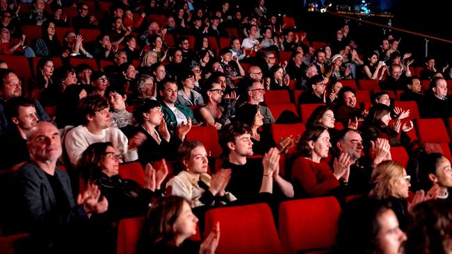 Ein großes Publikum sitzt in roten Kinosesseln und applaudiert in einem abgedunkelten Saal bei der  „Diagonale“.