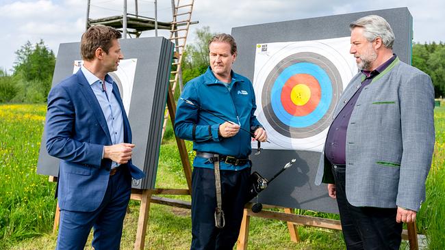 © ORF/ZDF/Linda Gschwentner Die Kommissare Hansen und Stadler erkundigen sich auf einem Bogenschießplatz vor Zielscheiben beim Bogenschützen Walter Hofmeister, ob er mit Jagdpfeilspitzen schießt.