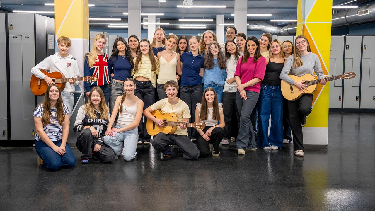 Gruppenfoto mit den Schüler:innen der 5a des Musikzweiges am BRG/BORG in Schwaz in Tirol, einige halten Gitarren, und Lisa Gadenstätter