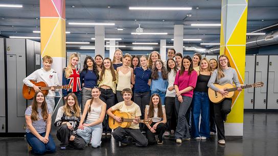 Gruppenfoto mit den Schüler:innen der 5a des Musikzweiges am BRG/BORG in Schwaz in Tirol, einige halten Gitarren, und Lisa Gadenstätter