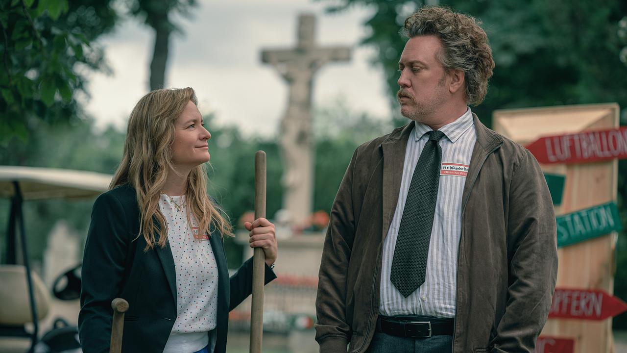 Ursula Fink mit einer Schaufel in der Hand steht neben Heli Wondratschek auf einem Friedhof.