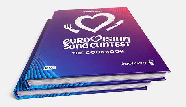 © ORF/Brandstätter Two stacked copies of the book “Eurovision Song Contest – The Cookbook” with a violet-blue cover