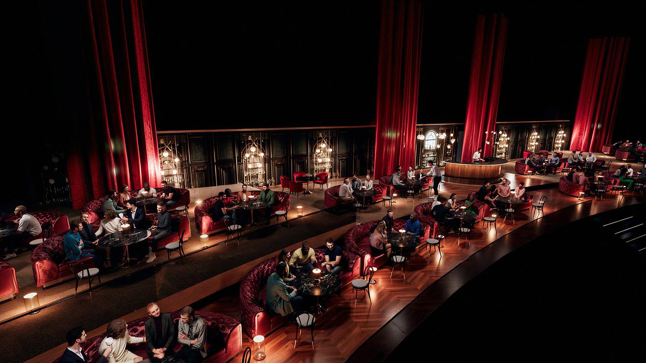 © Kaffeehaus-Charme im Green Room: Die Gesamtansicht zeigt mehrere Ebenen mit roten Sitzgruppen, warmem Licht und zahlreichen Gästen.