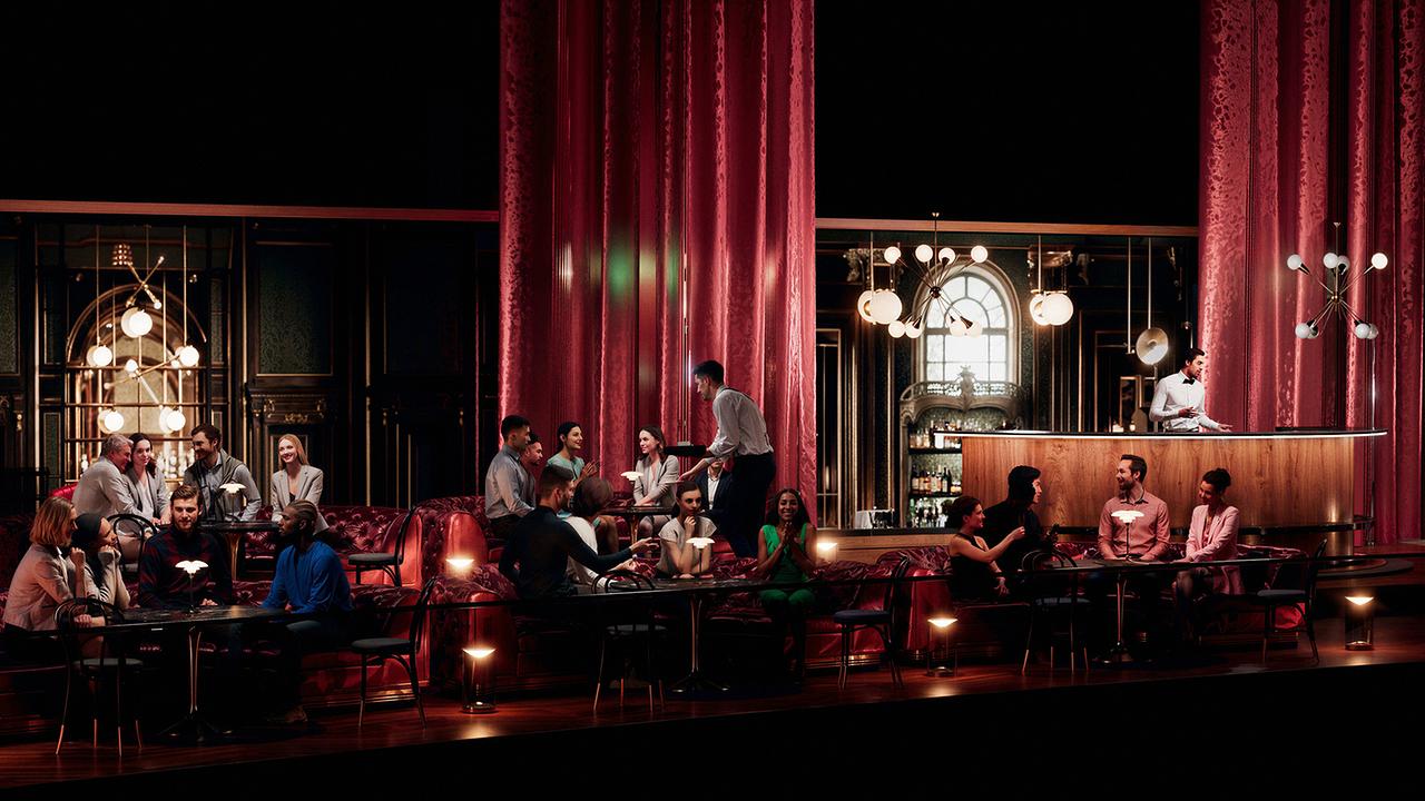 © Kaffeehaus-Charme im Green Room mit roten Samtvorhängen und -sofas, in dem Gäste an kleinen Tischen sitzen, bedient von Servicepersonal, mit einer stilvollen Bar im Hintergrund.