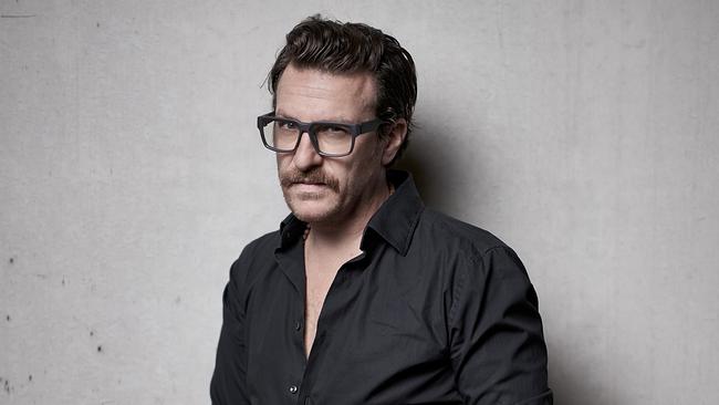 © ORF/Roland von der Aist Parov Stelar in einem schwarzen, leicht geöffneten Hemd posiert vor einer hellgrauen Wand und blickt leicht zur Seite.