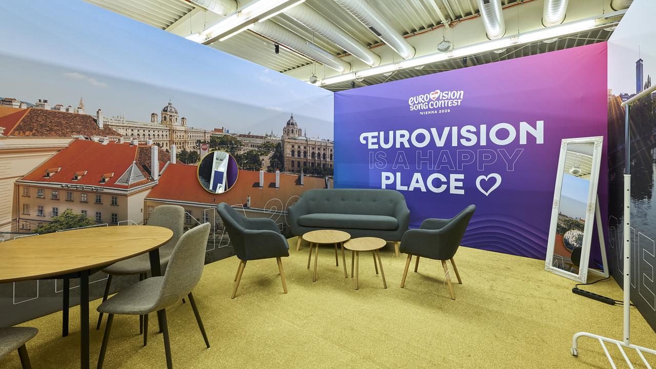 The Delegation Bubble in the Wiener Stadthalle: A modernly designed lounge with sofa, armchairs and tables is decorated with large-scale Vienna motifs and the lettering "Eurovision is a happy place".
