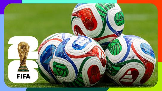 Mehrere bunte Fußbälle liegen auf grünem Rasen, links daneben das FIFA‑Logo mit dem Fußball-WM‑Pokal vor einem farbig gestalteten Rahmen.
