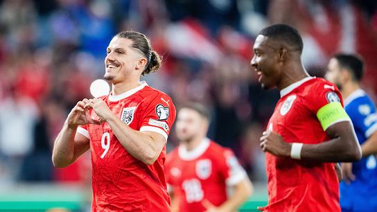 Marcel Sabitzer formt mit seinen Händen ein Herz und jubelt mit David Alaba und weiteren Teamkollegen in roten Trikots auf dem Spielfeld nach seinem Elfmeter während des Spiels zur WM-Qualifikation zwischen Österreich und Zypern in Linz.