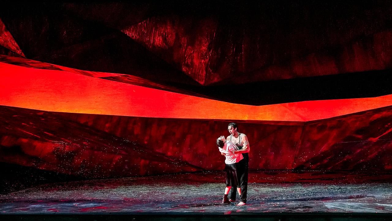 Szene aus "Georges Bizet - Carmen", in der Asmik Grigorian und Jonathan Tetelman auf einer von Rot- und Schwarztönen dominierten Bühne innig miteinander agieren.