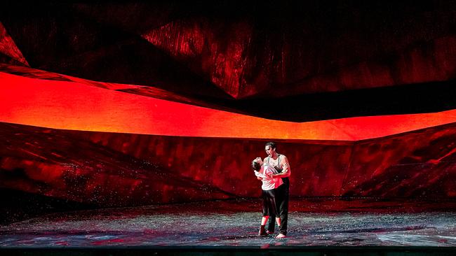 Szene aus "Georges Bizet - Carmen", in der Asmik Grigorian und Jonathan Tetelman auf einer von Rot- und Schwarztönen dominierten Bühne innig miteinander agieren.