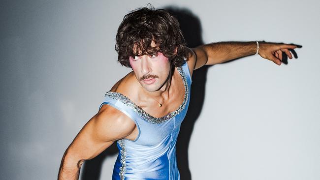 © ORF/Jeremy Kees Orr Go-Jo in einem hellblauen, glänzenden Ganzkörperanzug balanciert auf einer Leiter und streckt einen Arm seitlich aus.