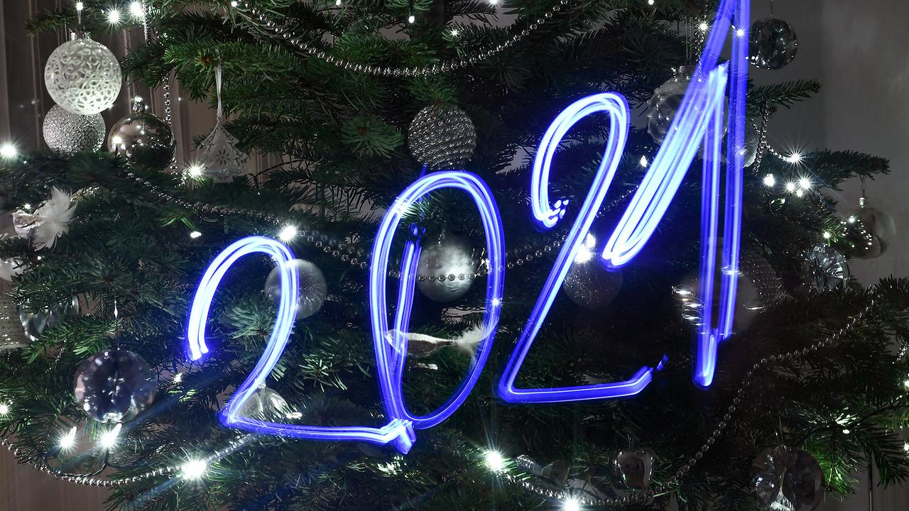  An illustration taken on December 30, 2020 in Budapest shows the numbers of the year 2021 painted with light in front of an illuminated Christmas tree