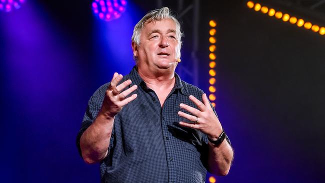 © ORF/Thomas Jantzen Andreas Vitásek steht gestikulierend auf einer beleuchteten Bühne, während farbige Scheinwerfer im Hintergrund leuchten.